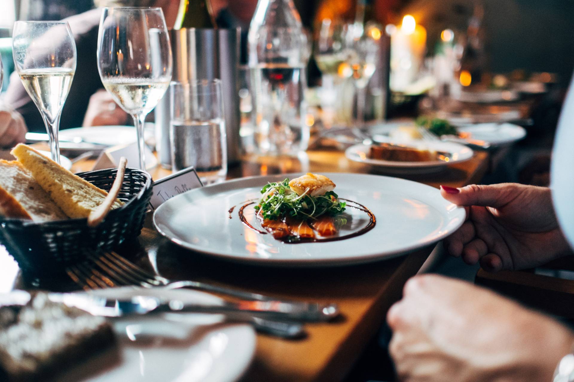 A person sitting over a gourmet meal at a long table with numerous plates and wine glasses