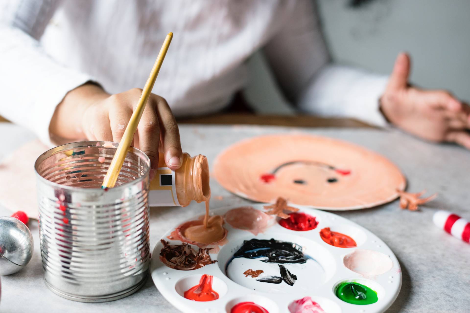 child's hand pouring paint into a paint palette