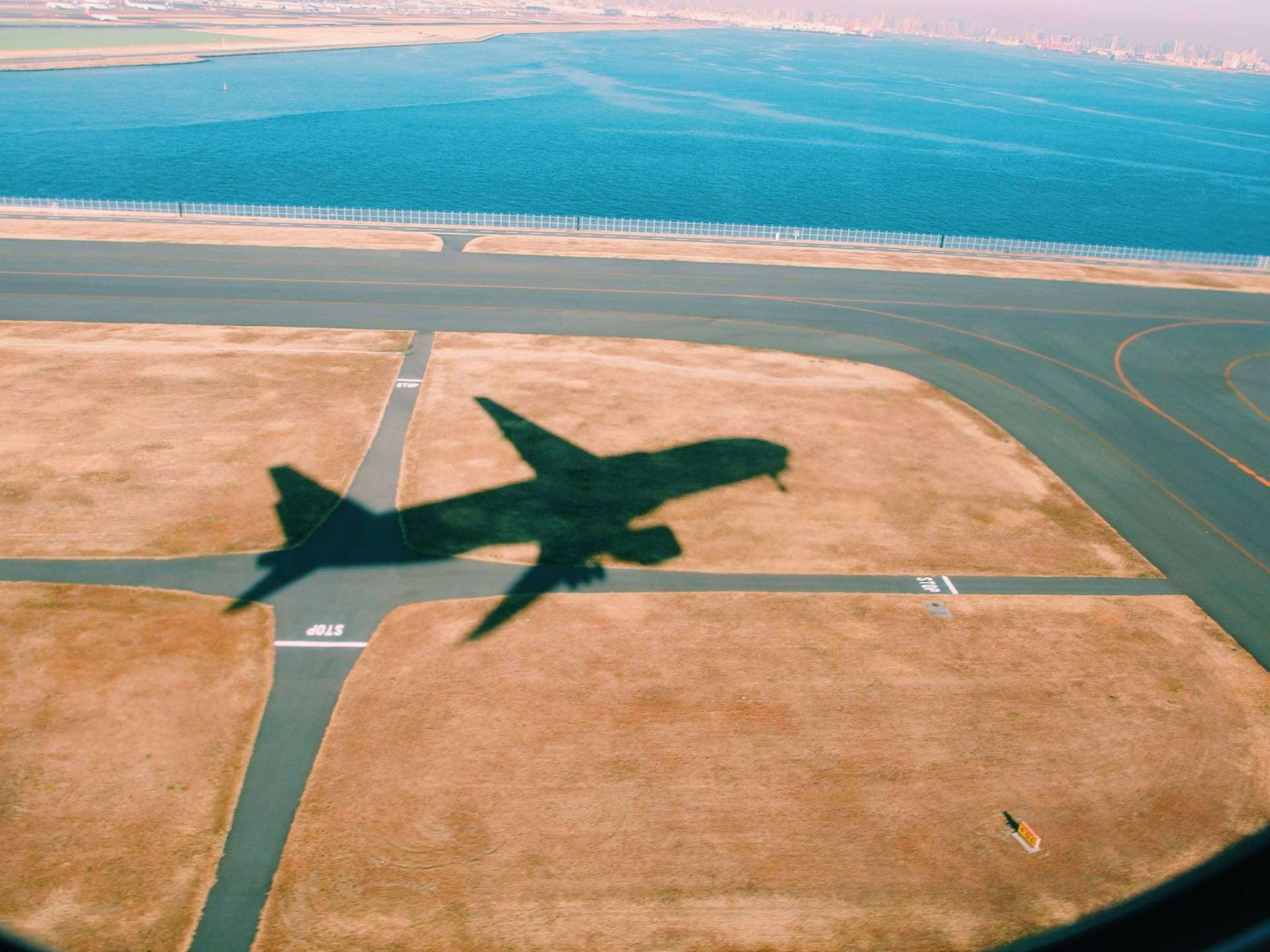 shadow of plan during take off over scorched grass and runway
