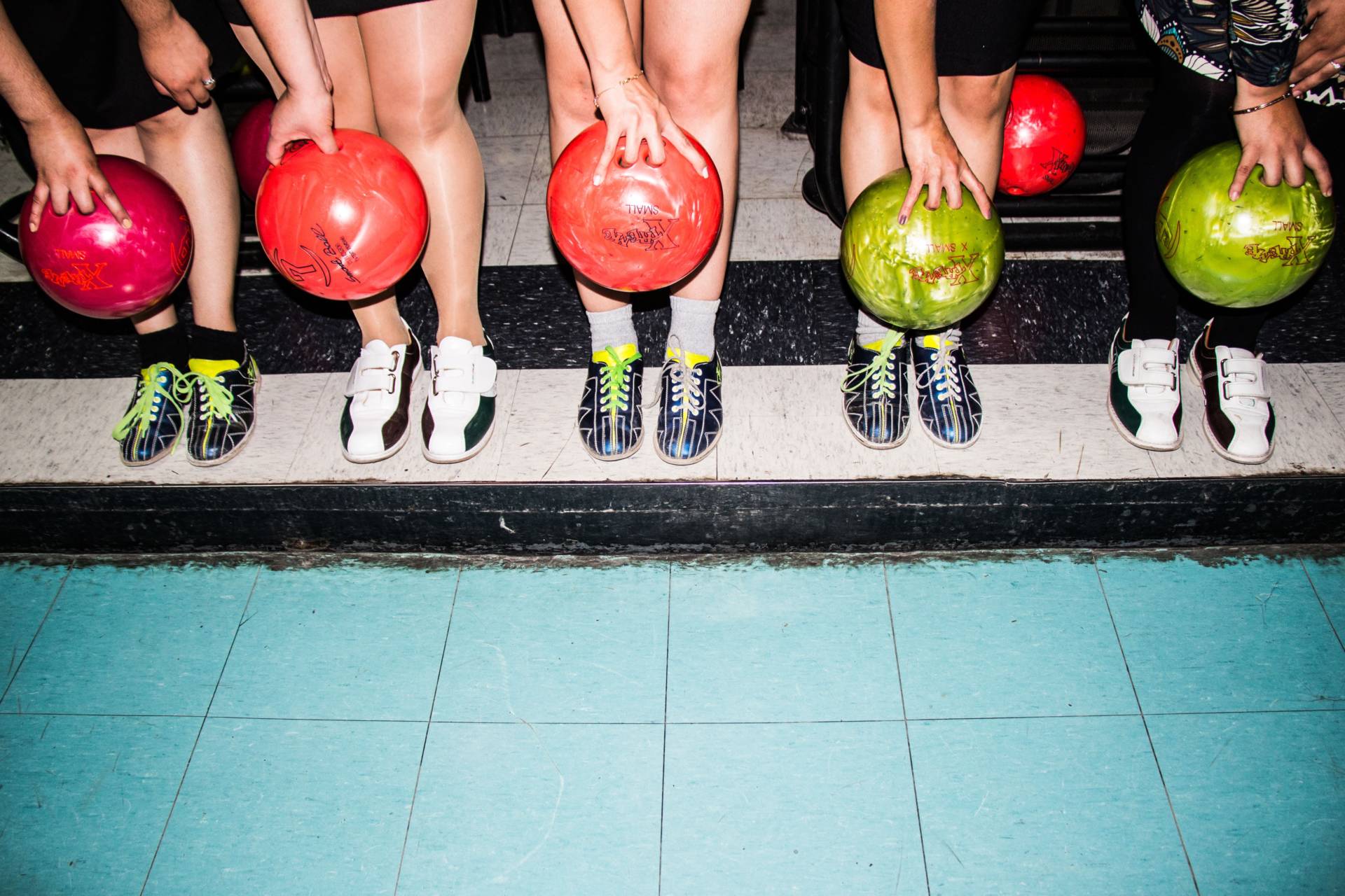 people stood in a line holding bowling balls