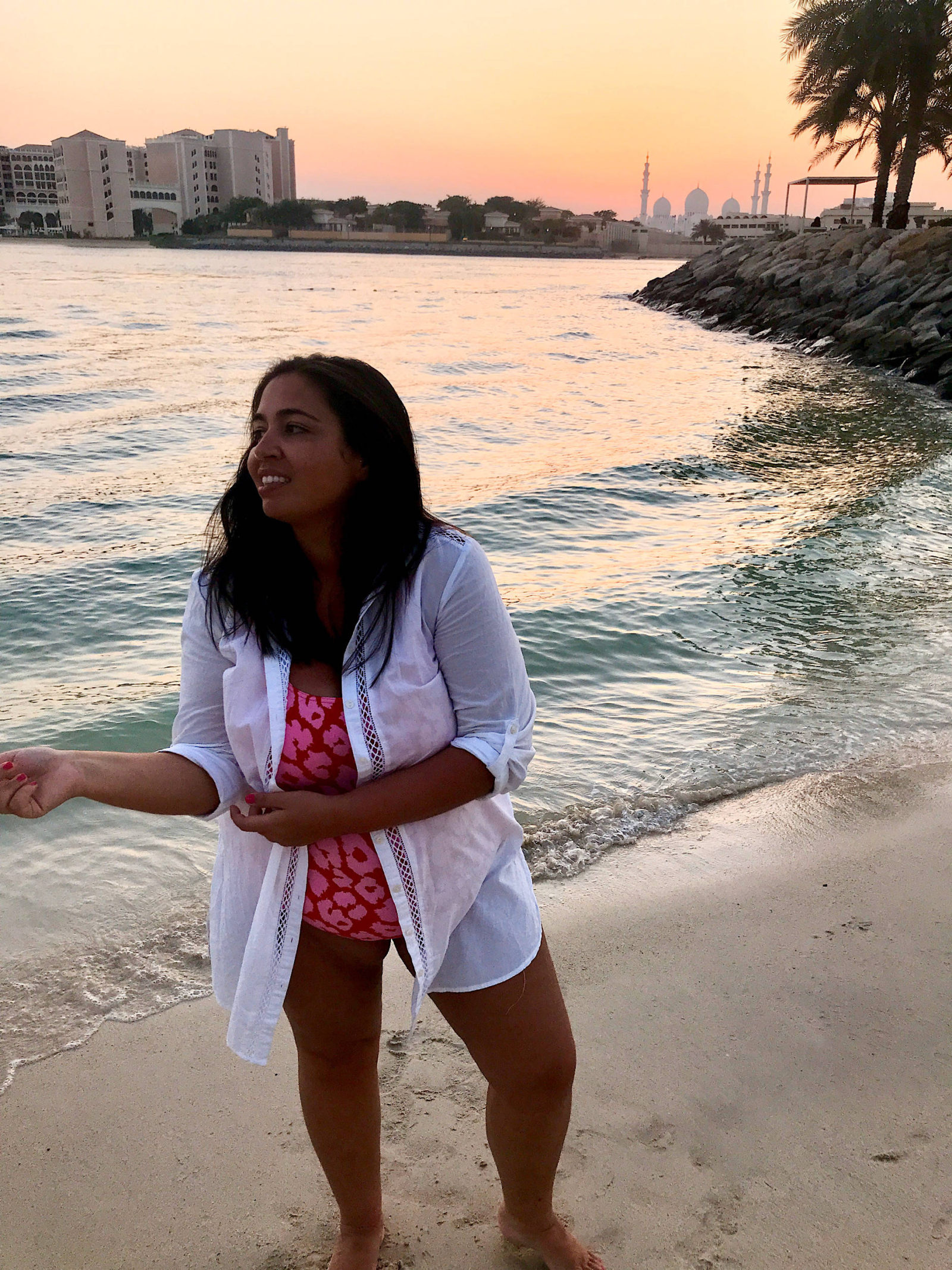 women standing on sandy beach at sunset with Shikh Zayd Mosque in Background