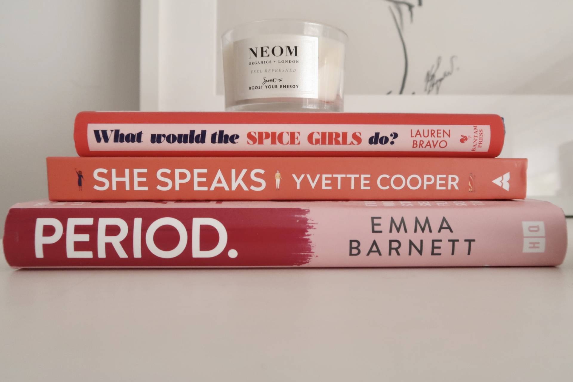 stack of pink and red books with an unlit candle on top