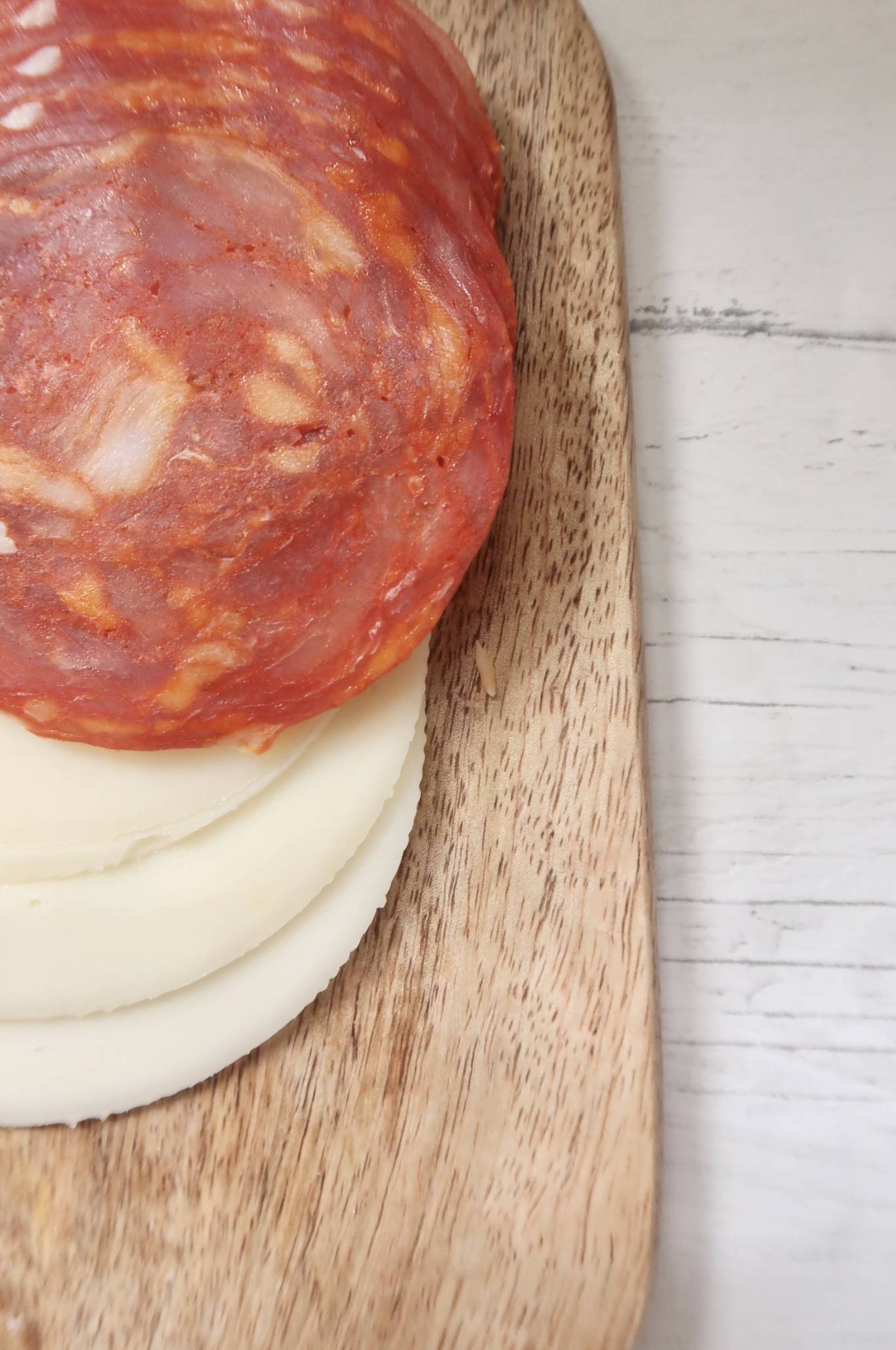 Sliced cheese and chorizo on wooden platter