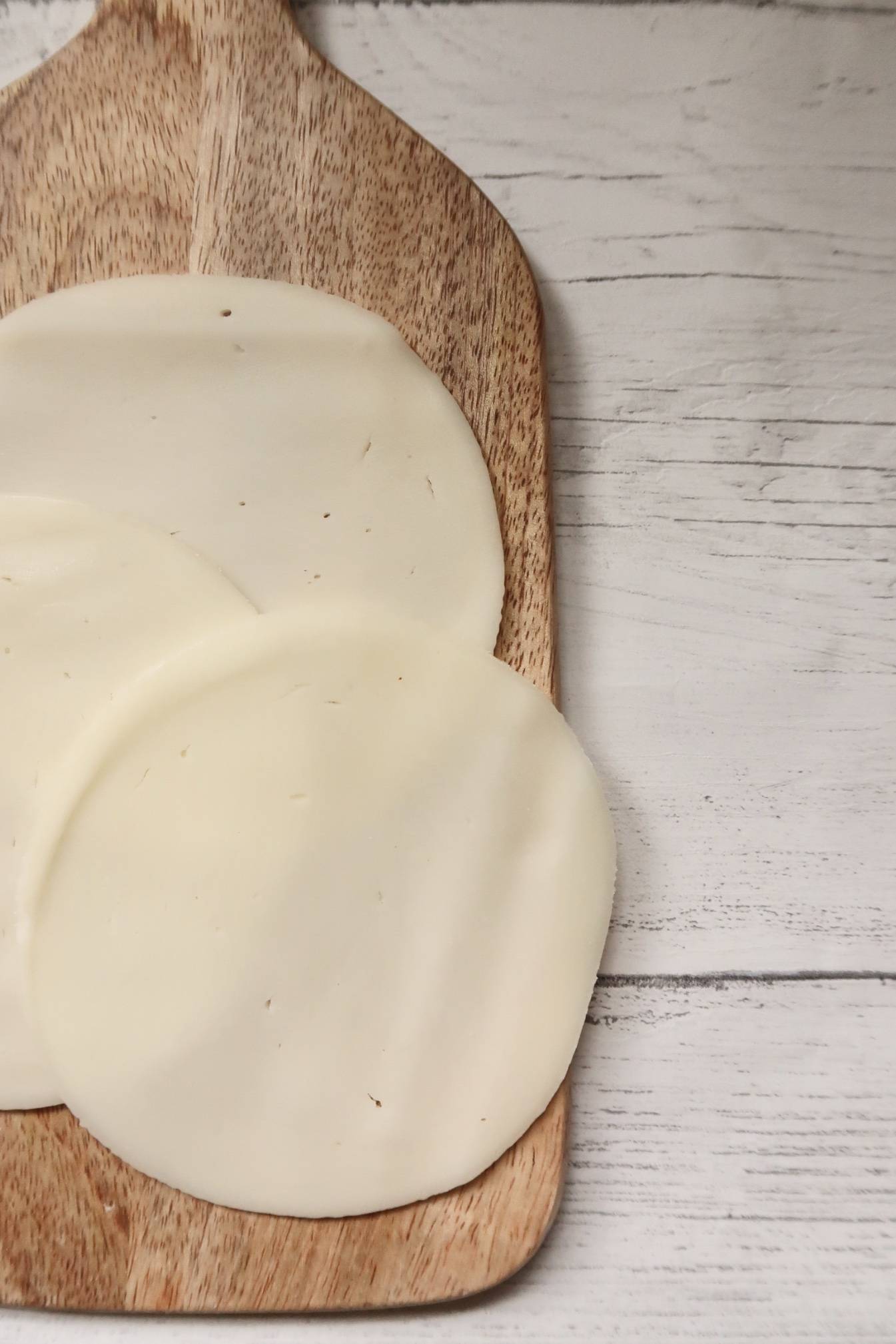 Sliced cheese on wooden serving board