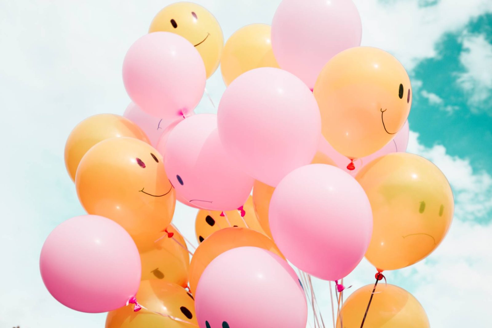 Bunch of pink and orange balloons with smiley faces drawn on