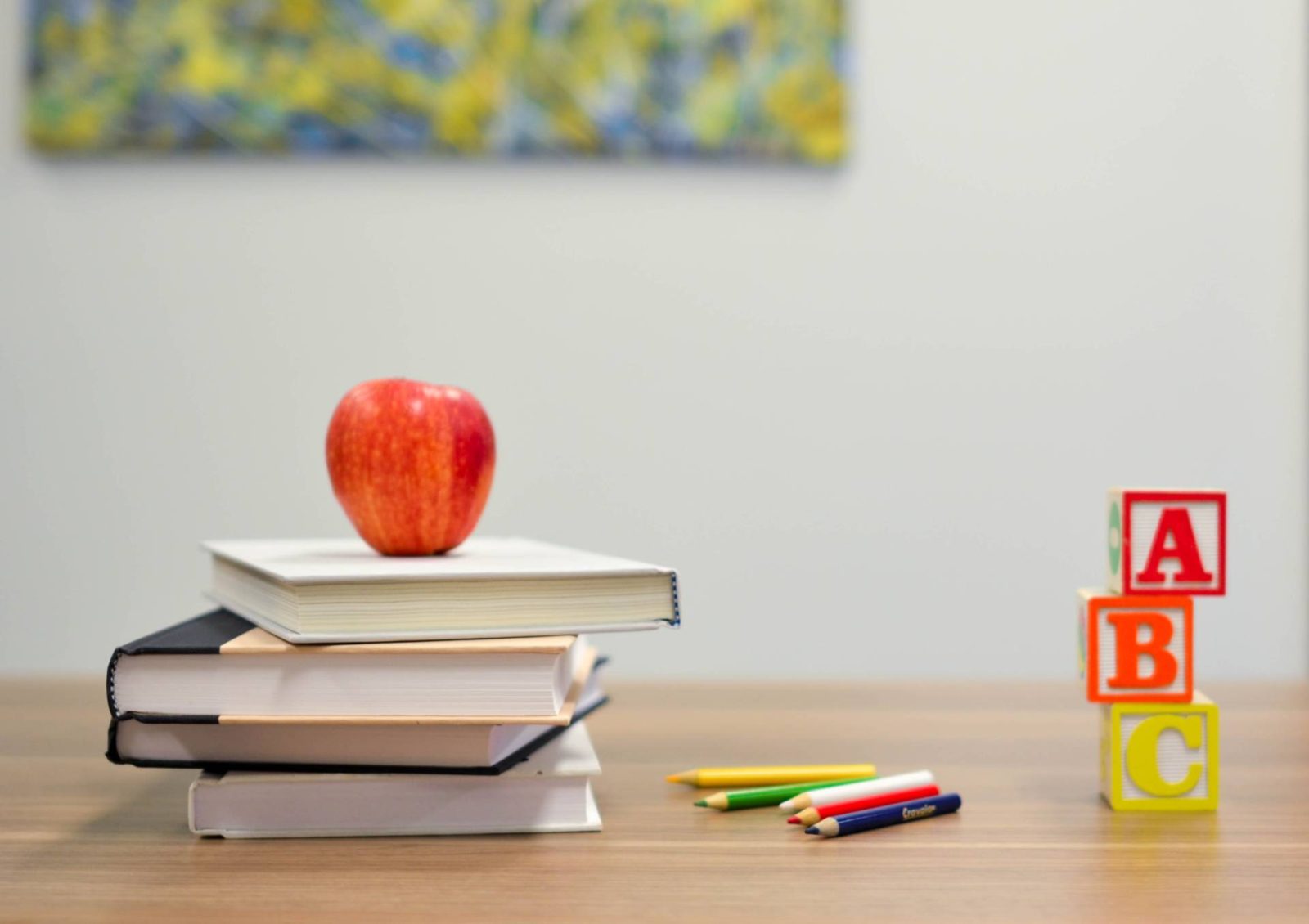 apple on pile of books next to abc blocks and crayons