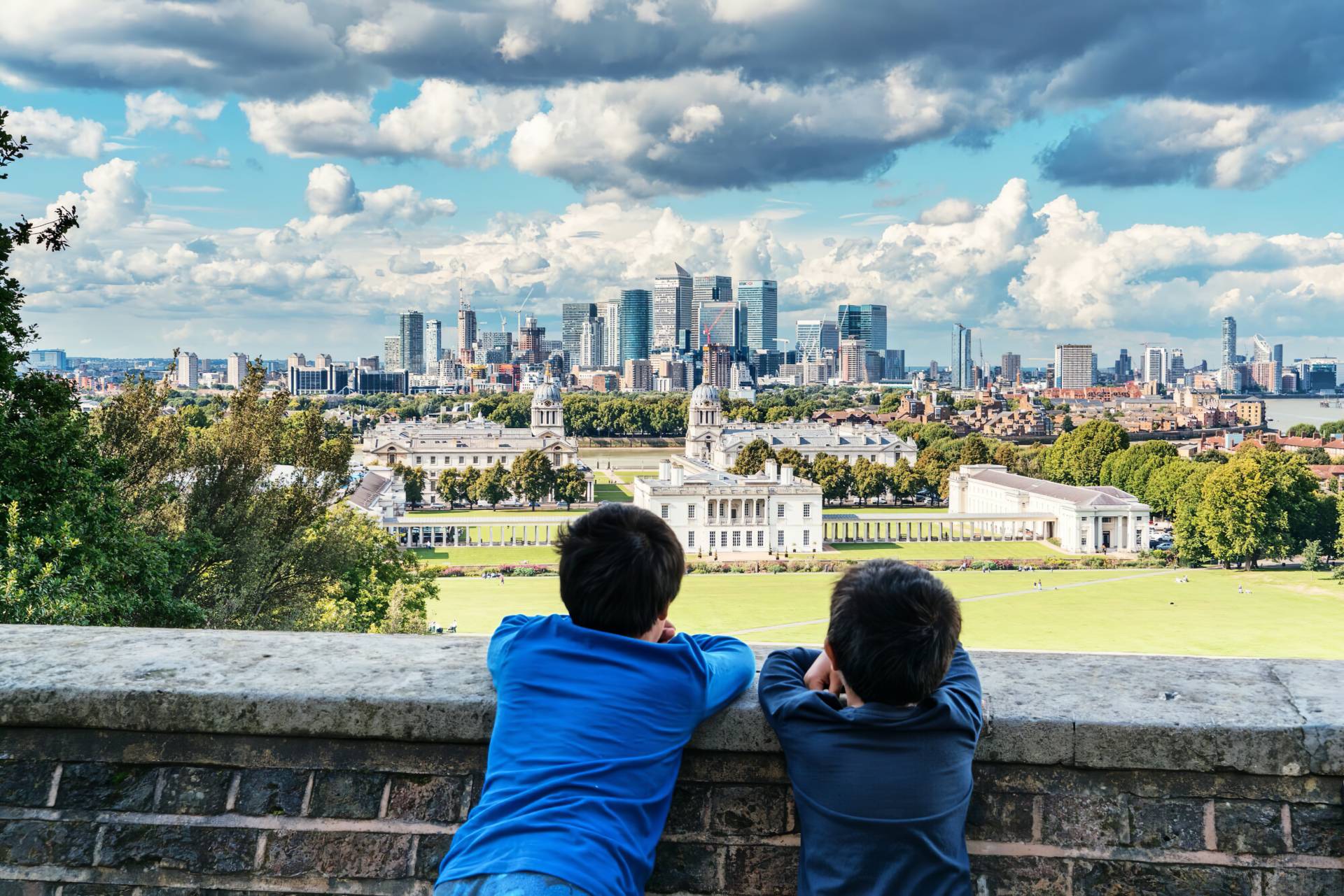 two dark haired boys looking out at London skyline in daytime