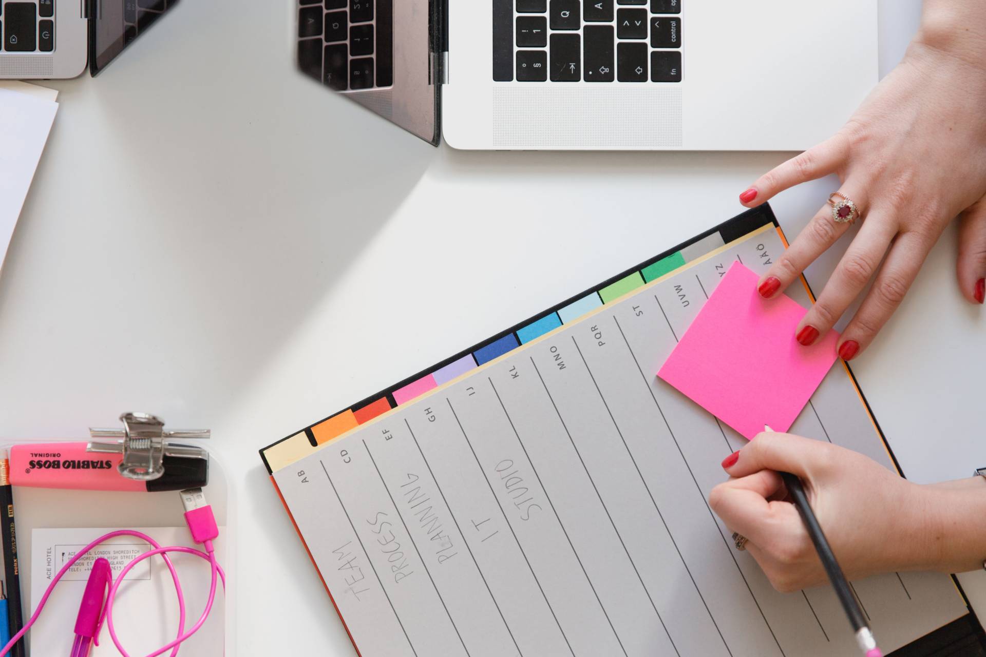 overhead shot of woman's hand making notes next to a laptop