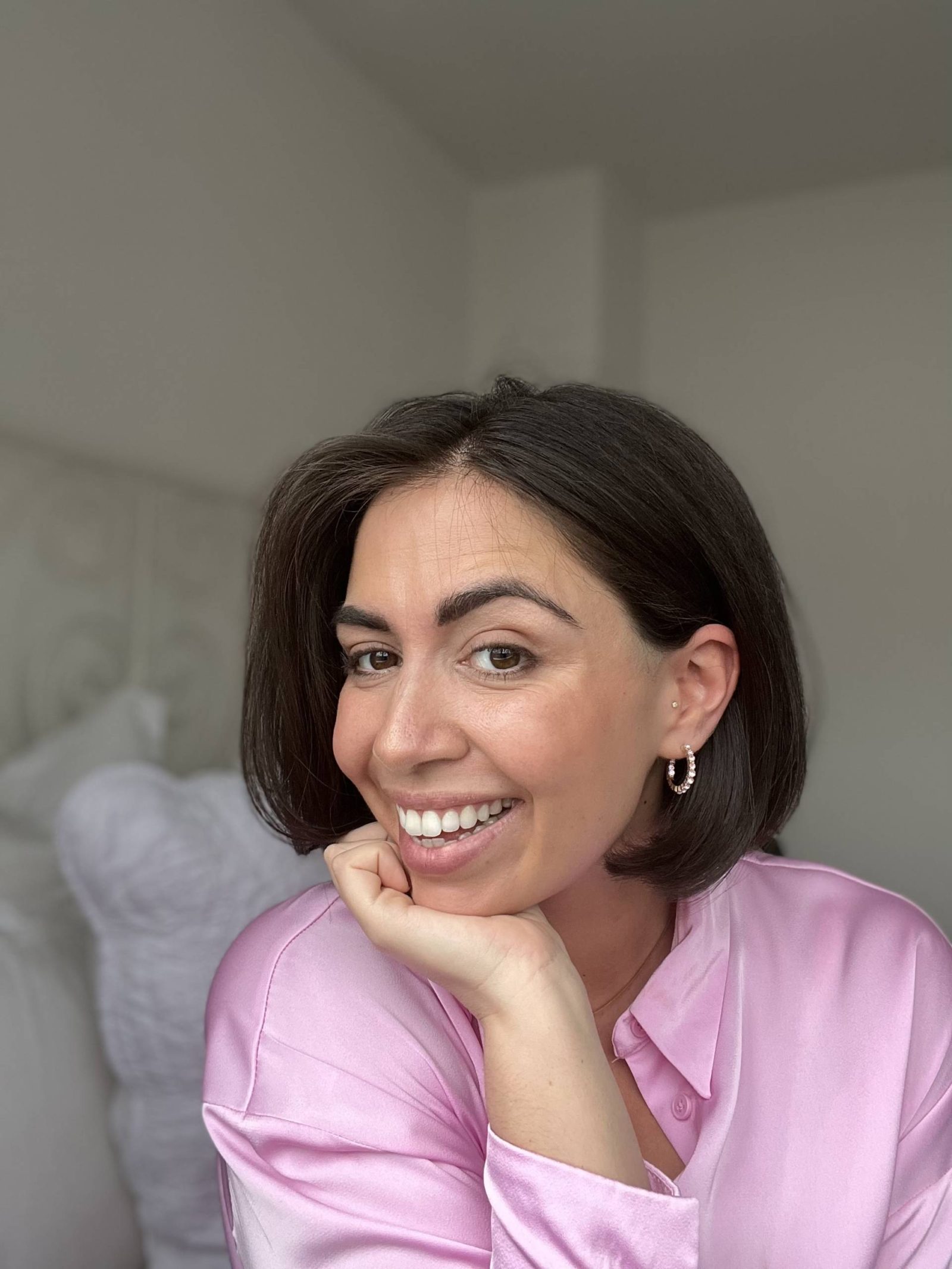 Woman with short brown hair smiling wearing pink shirt