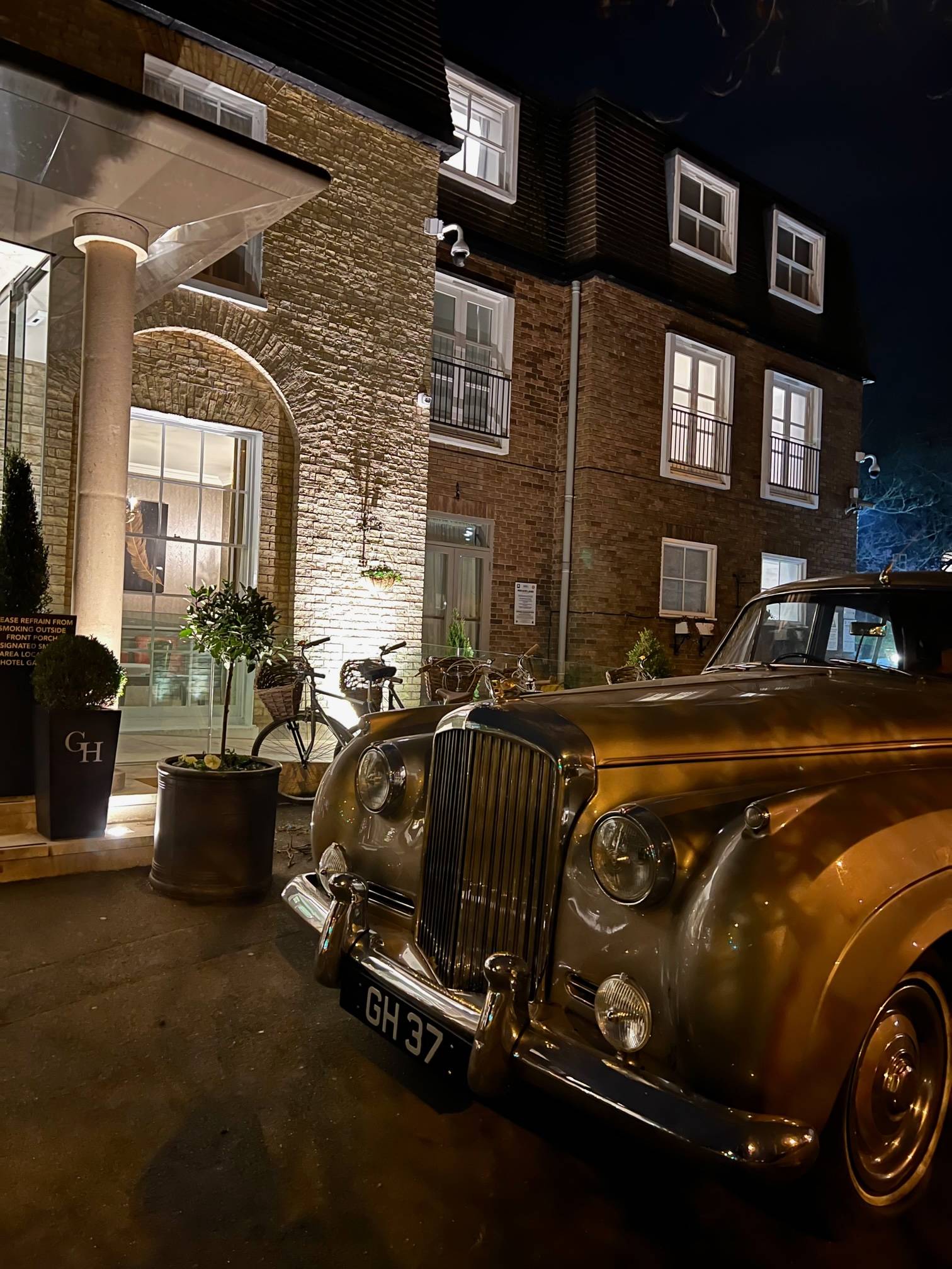 silver Bentley car outside a hotel entrance 