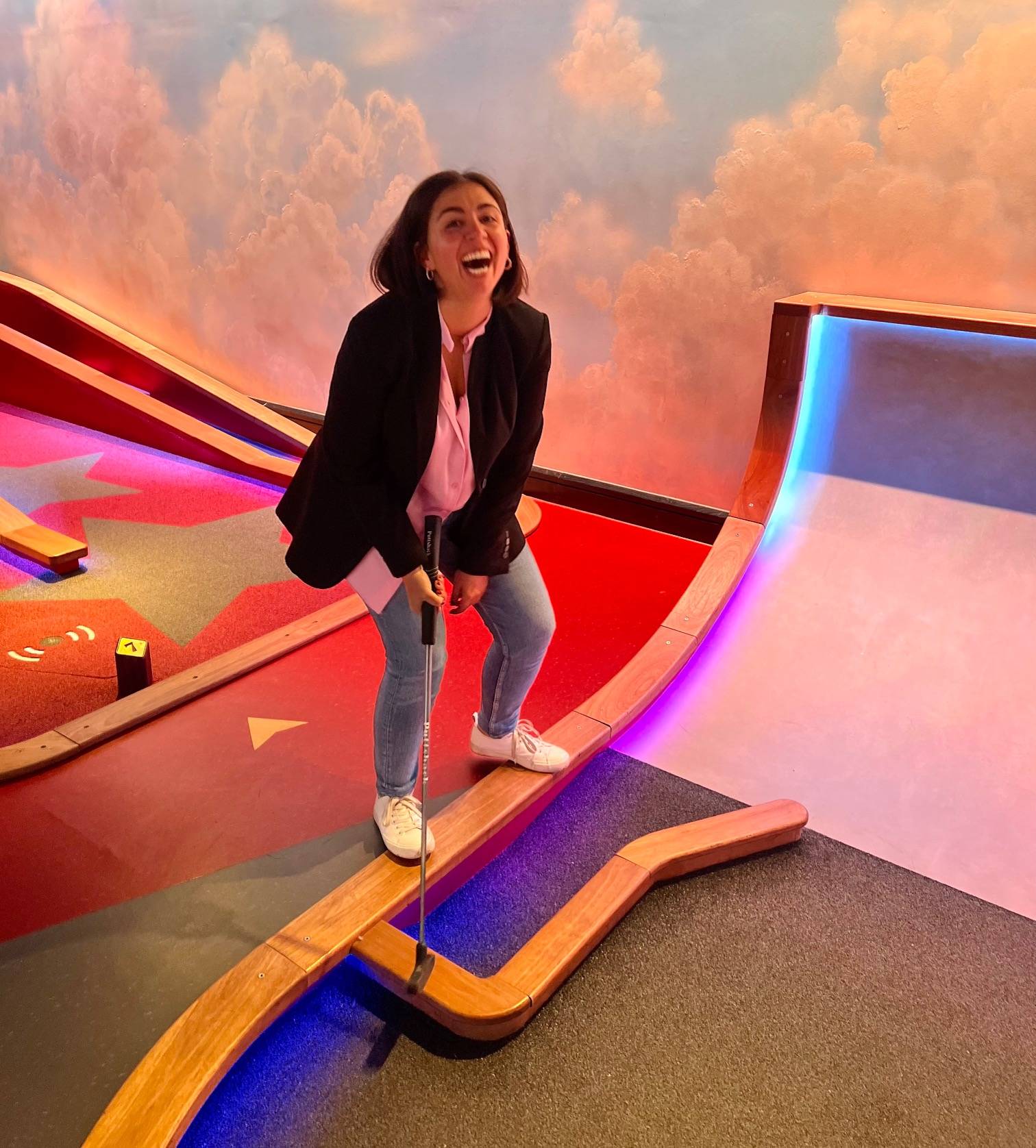 Woman holding mini golf club laughing