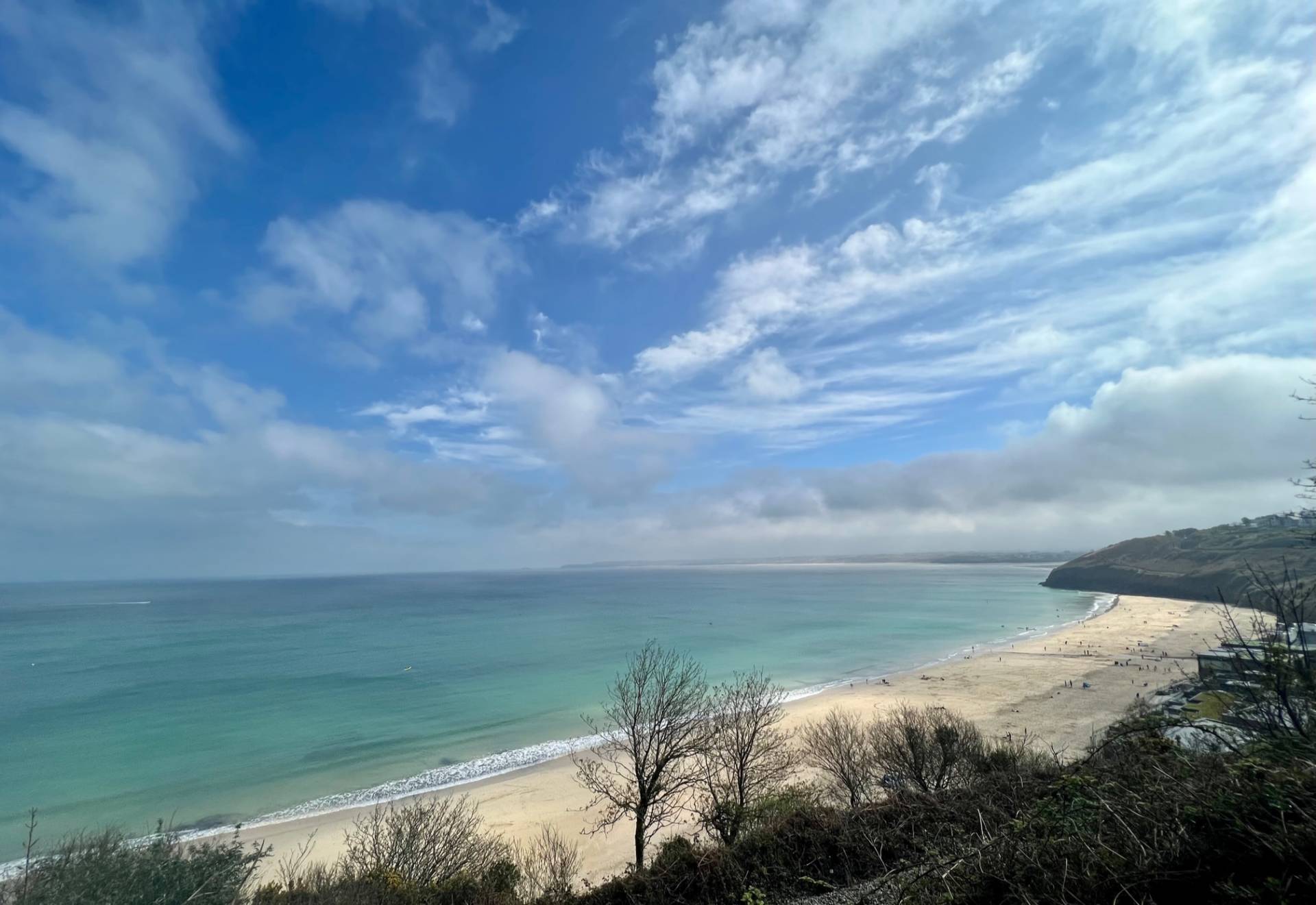 View of beach bay, turquoise water, golden sand and blue sky