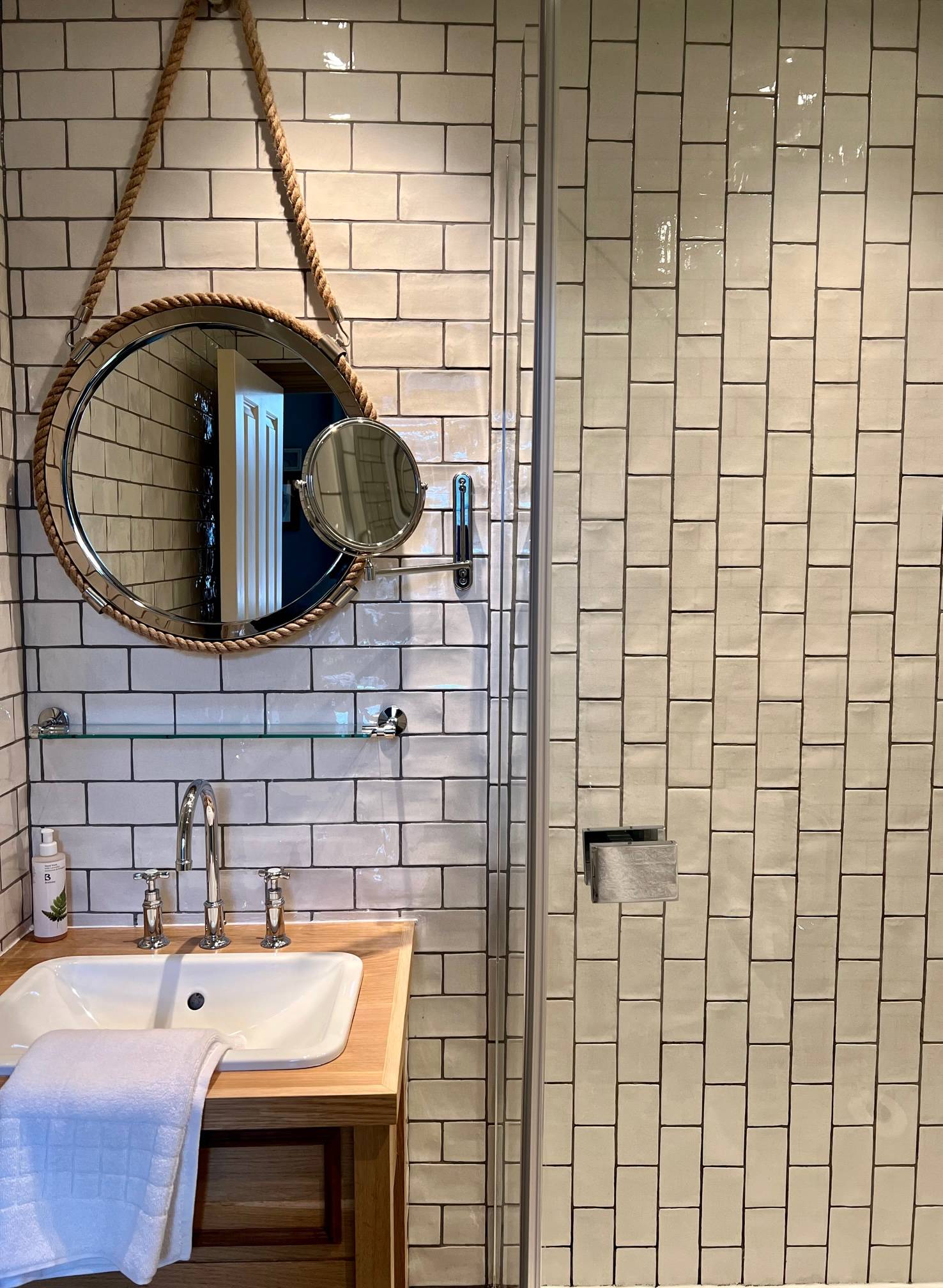 white meetro tiled shower room with basin and round mirror 