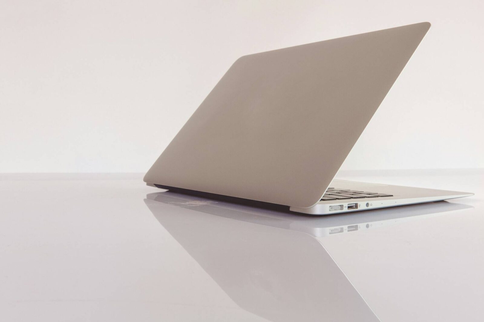 partially open silver laptop on a white gloss surface and background 
